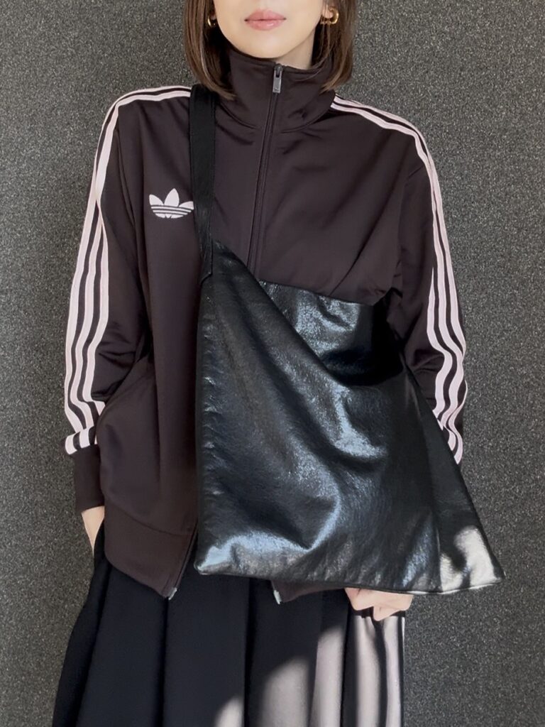 adidas Originalsトラックジャケットに黒サテンパンツと大きめレザーバッグを合わせたスポーティミックスなモードコーデ